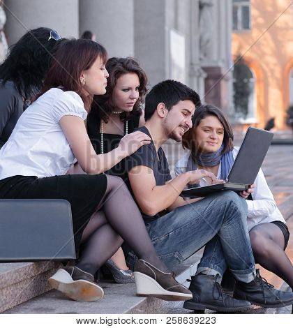 Group Of Fellow Students With Books And Laptop