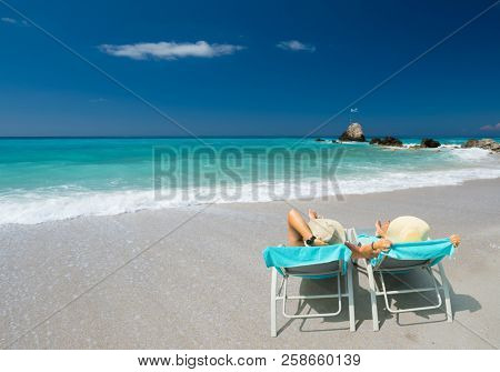 Couple on sunbeds relaxing at the beach in Lefkada Greece