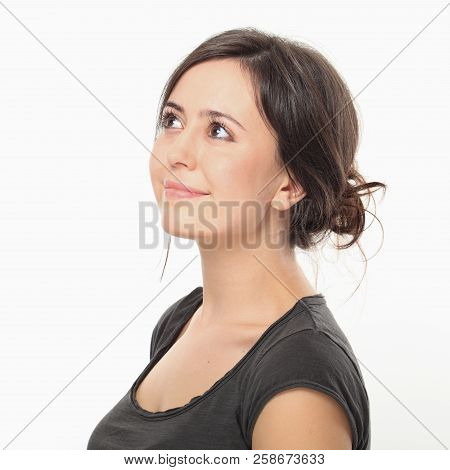 Dreamly Pretty Woman Looking Upwards Against White Wall