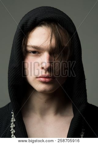 Guy On Confident Face In Black Hood, Grey Background. Macho In Black Bathrobe With Hood, Close Up. M