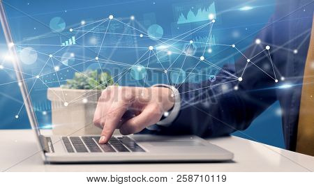 Businessman typing on laptop with linked reports charts grapghs around