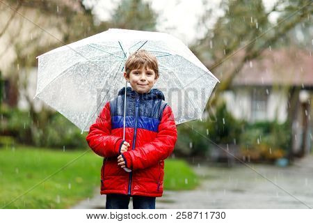 Little Blond Kid Boy On Way To School Walking During Sleet, Rain And Snow With An Umbrella On Cold D