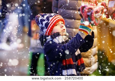 Little Cute Kid Boy Buying Sweets From A Cancy Stand On Christmas Market