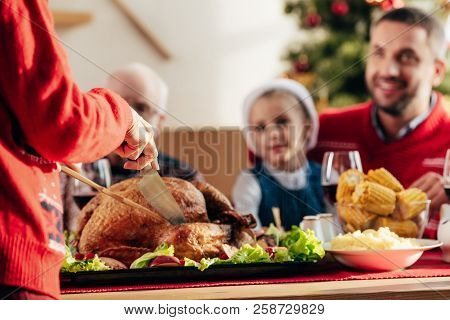 Cropped Image Of Woman Slicing Delicious Tukey For Christmas Dinner With Happy Family At Home