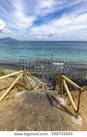 Steps Leading Down To A Swing At Blue Stone Beach In Flores, Indonesia.