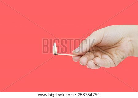 Burning Match In Hand On Red Backgroound. Hand Holding Matchstick. Isolated On Red