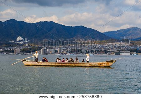 Miyajima, Japan - Feb 03, 2018: Tourists And Locals In A Boat With Two Japanese Men With Paddles Sai