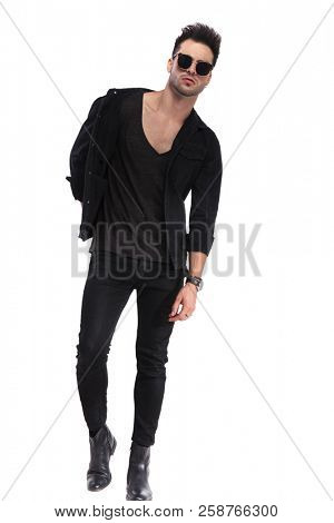 sexy young man wearing black clothes and sunglasses stepping forward on white background