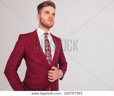 portrait of a confident young sexy businessman posing on grey background, side view