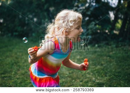 Kid Child  Trying To Catch Eat Soap Bubbles With Tongue. Candid Portrait Of Cute Funny Little Blond 