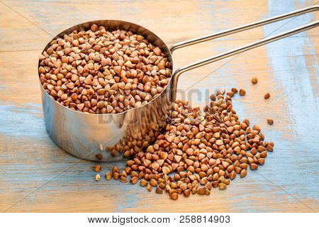 glutn free buckwheat kasha in a measuring scoop (1/4 cup) against wood background