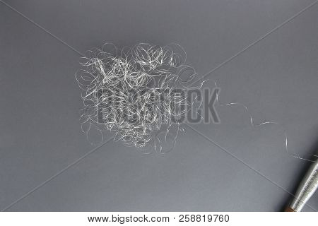 Silver Thread Pile Like Cloud And Spool Of Silver Thread. Pile Of Silver Thread On Grey Background.