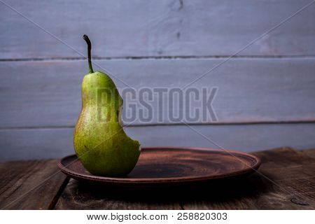 A Bite Pear On A Plate On Wooden Background