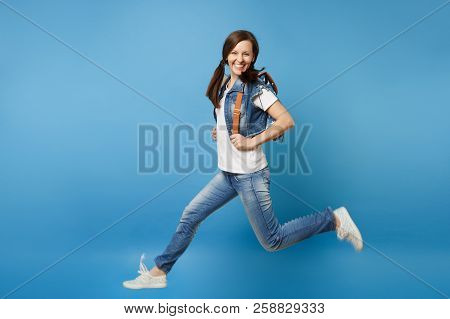 Full Length Portrait Of Young Funny Pretty Smiling Woman Student In Denim Clothes With Backpack Jump