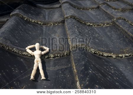 Wooden Doll Sleeping Face Up On A Asian Roof Tiles