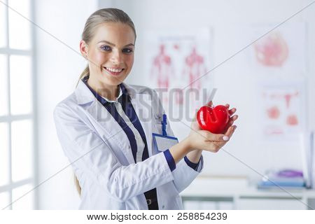 A doctor with stethoscope examining red heart, isolated on white background