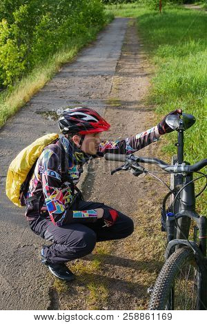 Photo Of Male Cyclist Wearing Helmet Next To Bicycle On Road In Woods During Day