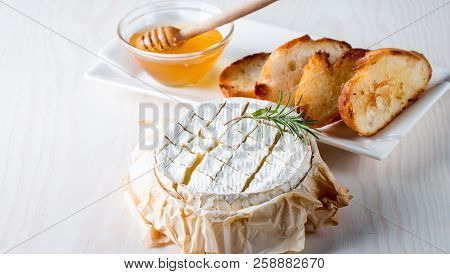 Baked Camembert Cheese. Fresh Brie Cheese And A Slice On A Wooden Board With Nuts, Honey, Rosemary, 