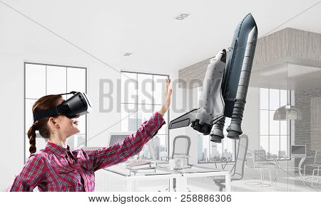 Young Caucasian Woman In Modern Office Interior Trying Virtual Reality Helmet And Viewing Space Shut