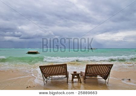 Dos tumbona en la playa de lluvia antes de la tormenta