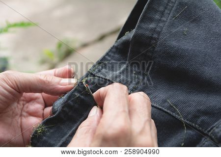 Hand Holding And Using Sewing Seam Ripper. Ripping A Seam With A Ripper.