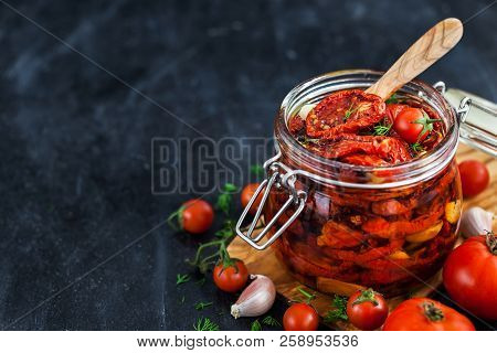 Sun Dried Tomatoes With Garlic And Olive Oil In A Jar On Dark Background