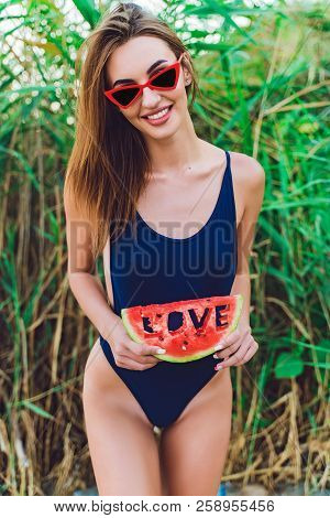 Beautiful Young Female In Swimsuit And Red Sunglassses Hold Slice Of Watermelon With Inscription Lov