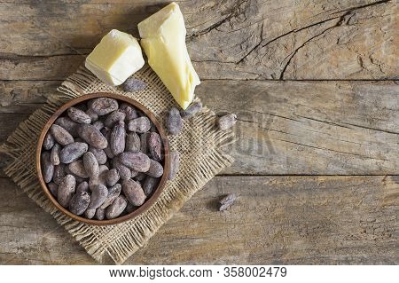 Cocoa Butter Or Cocoa Bean Solid Oil With Cacao Powder In Spoon Or Bowl And Raw Cocoa Beans On Rusti