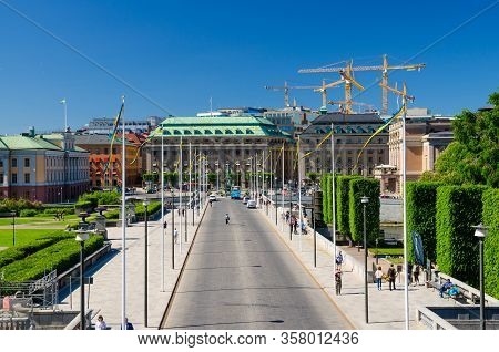 Sweden, Stockholm, May 31, 2018: Riksplan Green Grass Lawn, Bushes And Street With National Flags On
