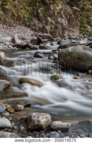 Long Exposure Of The River Flowing Over The Rocks On The Beach At Heddons Mouth In Exmoor National P