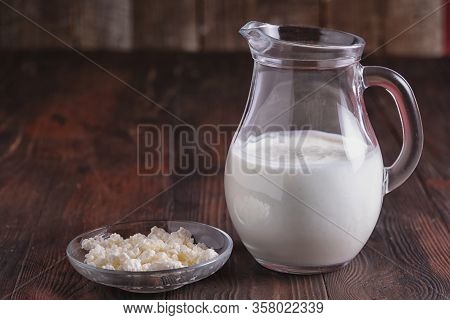 Top View Fermented Drink Kefir In A Glass Jar And Milk Curd In A Glass Plate On Brown Wooden Table.