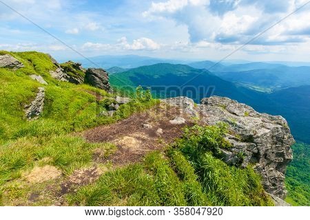 View In To The Valley From The Top Of A Mountain. Huge Rocks On The Grassy Hillside. Clouds On The S