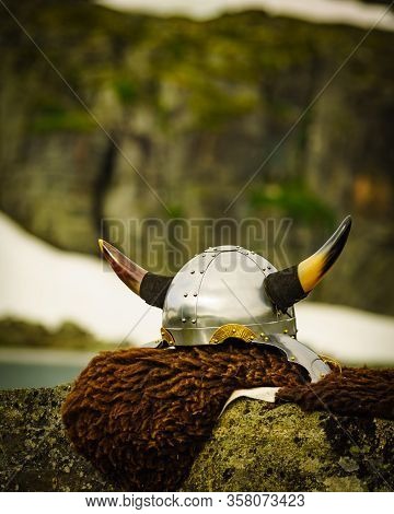 Equipment Of Viking Or Barbarian Warrior Outdoor On Nature. Viking Helmet On Brown Fur Of Animal In 