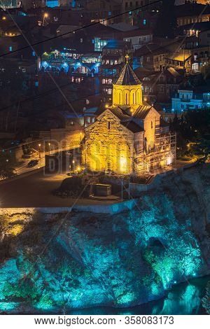Tbilisi, Georgia. Night Evening Illuminated View Of Metekhi Church And Equestrian Statue Of King Vak