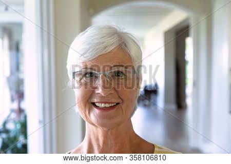 Portrait close up of a senior Caucasian woman with short grey hair wearing glasses smiling to camera at home. Family enjoying time at home, lifestyle concept
