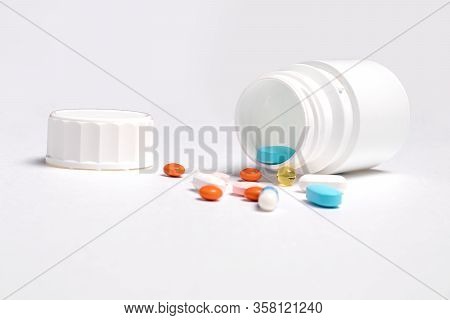White plastic bottle with medicines and vitamines. tematic health. rose, yellow and red medicines.