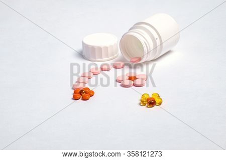 White plastic bottle with medicines and vitamines. tematic health. rose, yellow and red medicines.
