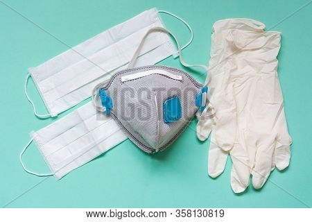 White Latex Gloves And Medicinal Facial Mask On Aquamarine Background.