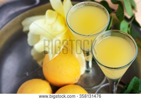 Limoncello In Elegant Liquor Glasses With Lemons, Mint And Yellow Rose On Steel Plate. Sicilian Lemo