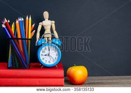 Two Red Books Stand On The Table, On The Books There Are Blue Watches And A Glass With Multi-colored
