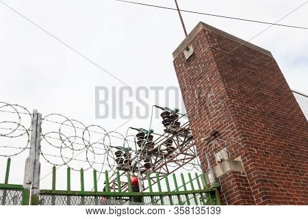 Electrical Power Facility Enclosed With Wrought Iron Fencing, Expanded Metal, And Razor Wire, Horizo
