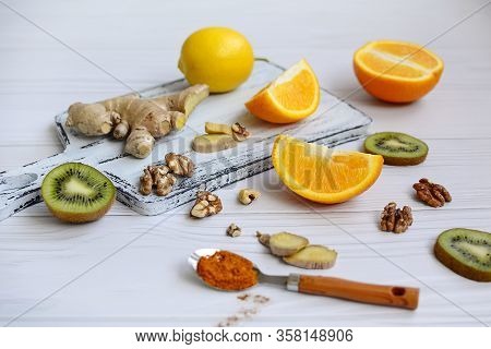 Lemons, Oranges, Kiwi, Ginger, Walnuts And Spices On A Light Wooden Background. The Concept Of Immun