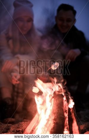 Winter Picnic On Baech With Bonfire. Love Story On Winter Foggy Sand Beach. Fry Marshmallows At The 