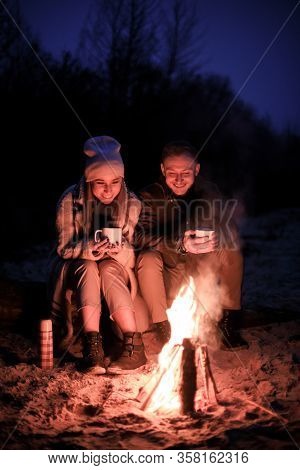 Winter Picnic On Baech With Bonfire. Love Story On Winter Foggy Sand Beach. Drink Hot Tea In Cold We
