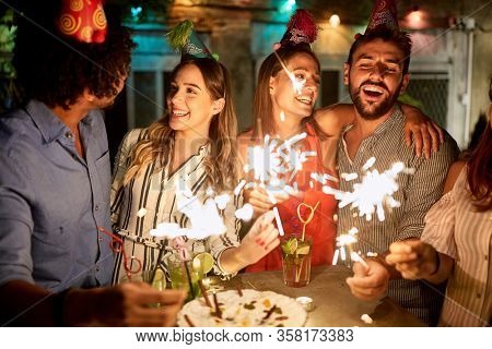 Happy female and male holding sparkles on birtday party