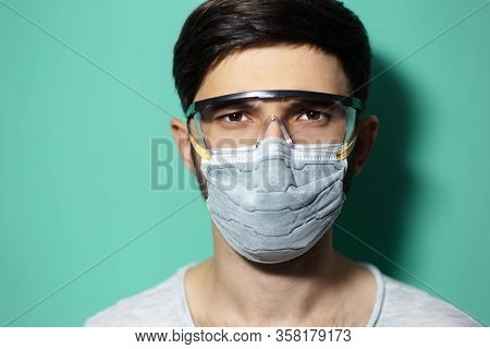 Studio Portrait Of Young Guy Wearing Medical Flu Mask And Safety Goggles, Coronavirus Prevention, Is