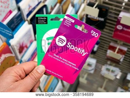 Montreal, Canada - March 24, 2020: Spotify Pink Gift Card In A Hand At Store Over Gift Cards. Spotif