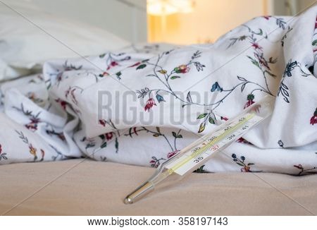  thermometer in bed showing fever coronavirus or COVID-19 