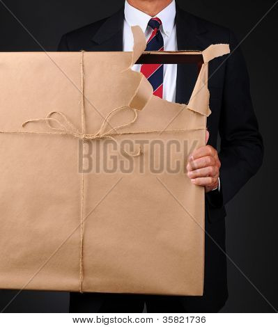 Nahaufnahme eines Mannes hält einen Bilderrahmen mit braunem Papier vor seinen Körper gewickelt. Papier ist tor