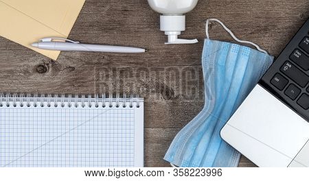 Hygiene In The Office. Remote Work Kit On Wooden Desk. Sanitizer Gel And Face Mask